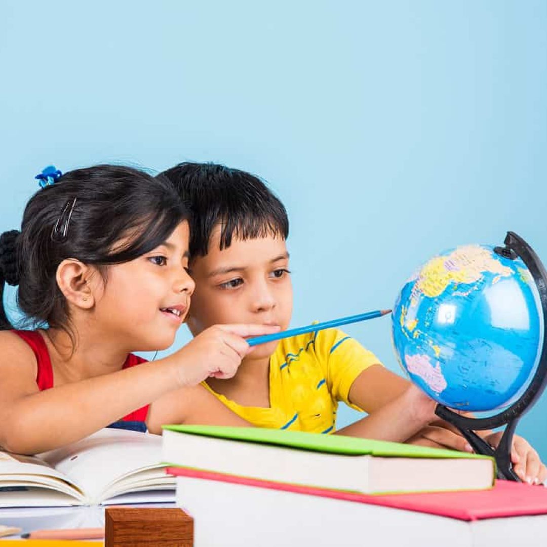cute-little-indian-asian-kids-studying-study-table-with-pile-books-educational-globe-isolated-light-blue-colour