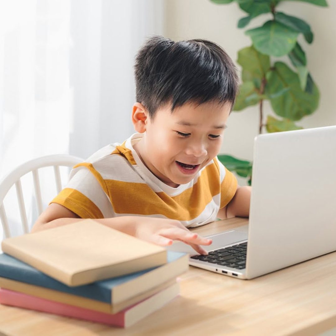 schoolboy-playing-online-game-laptop-home-sitting-table-preteenfree-time